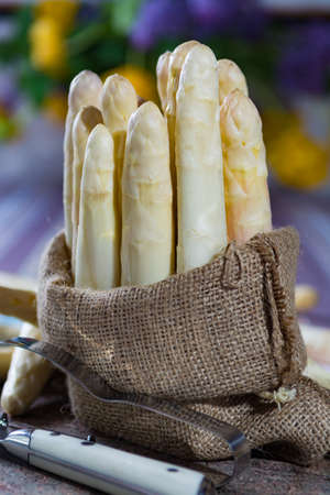 Spring season - fresh white big asparagus in burlap sack on granite plank backgroundの写真素材
