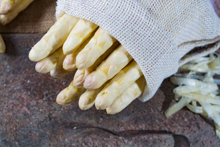 Spring season - fresh white big asparagus in burlap sack on granite plank backgroundの写真素材