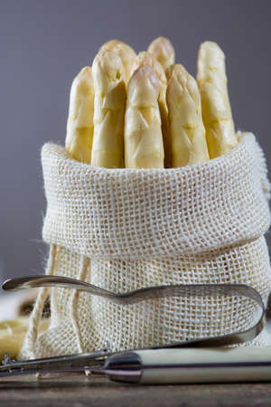 Spring season - fresh white big asparagus in burlap sack on granite plank backgroundの写真素材