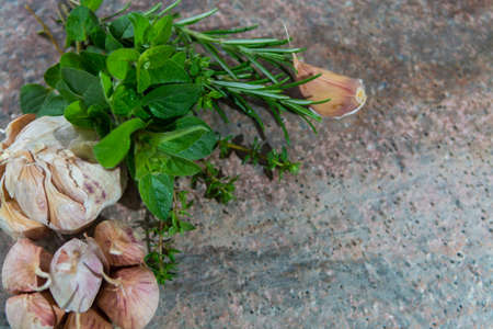 French dried violet garlic and fresh garden herbs on granite plankの写真素材