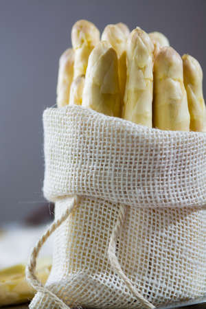 Spring season - fresh white big asparagus in burlap sack on granite plank backgroundの写真素材