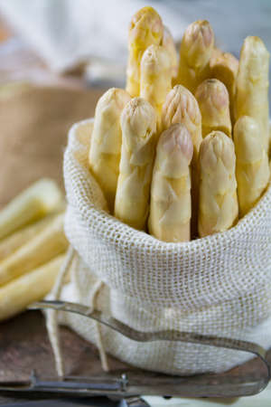 Spring season - fresh white big asparagus in burlap sack on granite plank backgroundの写真素材