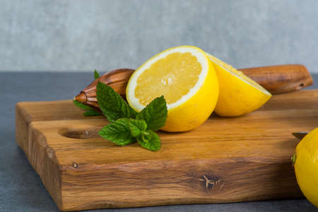 Ripe juicy yellow lemons witn juicer stick made from olive tree wood