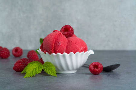 Raspberry ice cream sorbet in white bowl with spoon, raspberry, mint leaves  copy spaceの写真素材