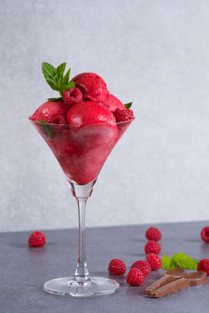 Raspberry ice cream sorbet in high glass with chocolate spoon, raspberry, mint leaves  copy spaceの写真素材