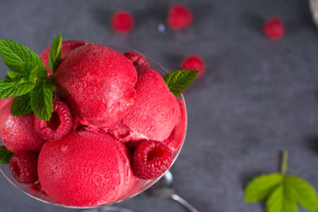 Raspberry ice cream sorbet in high glass with spoon, raspberry, mint leaves  copy spaceの写真素材