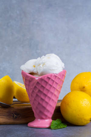 Lemon ice cream sorbet served for dessert on wooden plank in pink coneの写真素材