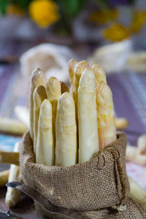 Spring season - fresh white big asparagus in burlap sack on granite plank backgroundの写真素材