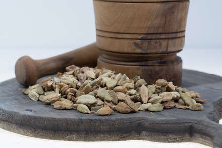 Raw Organic Cardamom Pods Ready to Use with mortar made from olive wood on white, copy spaceの写真素材