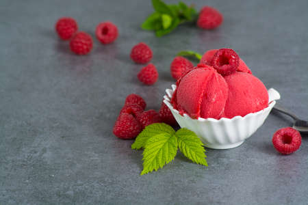 Raspberry ice cream sorbet in white bowl with spoon, raspberry, mint leaves  copy spaceの写真素材