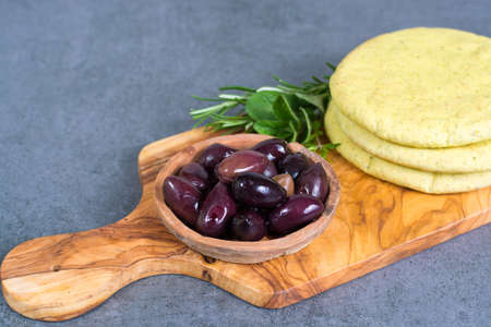 Mediterranean appetizer antipasti tapas calamara olives and garlic pita bread, herbs on wooden plank made from olive tree and grey backgroundの写真素材