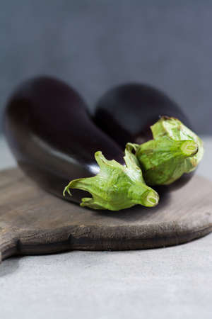 Two raw eggplants or aubergins vegetables, ready to cook on wooden backgroundの写真素材