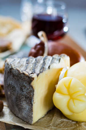 Sweet dessert liqueur wine in glass, hard cheeses Caciocavallo or Provolone, Tomme de Montagne, dried figs with figs bread, still life on wooden platterの写真素材