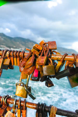 Love padlocks or love locks on a bridge in the harbor of Cefalu on blurred sunlight sea backgroundの写真素材