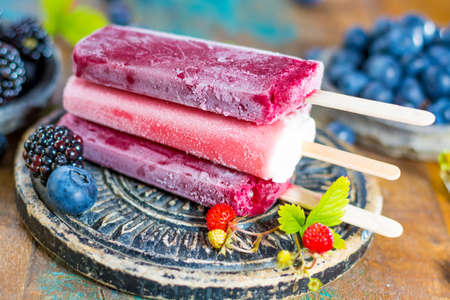 Fresh summer wild blueberries and  brambleberry, strawberry and home made sorbet ice cream popsicles.の写真素材