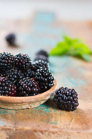 Fresh summer wild blackberries with leaves on wooden backgroundの写真素材