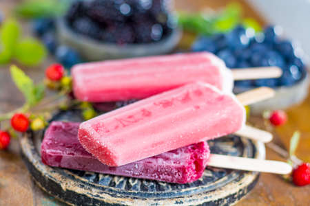 Fresh summer wild blueberries and  brambleberry, strawberry and home made sorbet ice cream popsicles.の写真素材