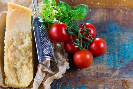 Traditional Italian hard cheese Parmesan with pasta, tomatoes, basil on wrapperの写真素材
