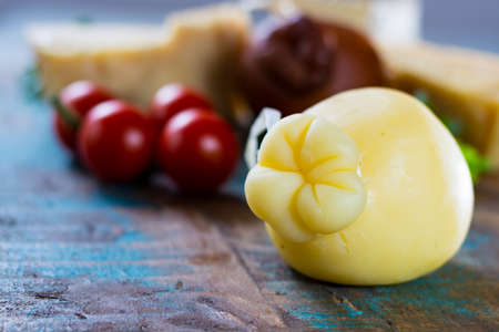 Traditional Italian hard cheese Provolone of Caciocavallo on wooden backgroundの写真素材