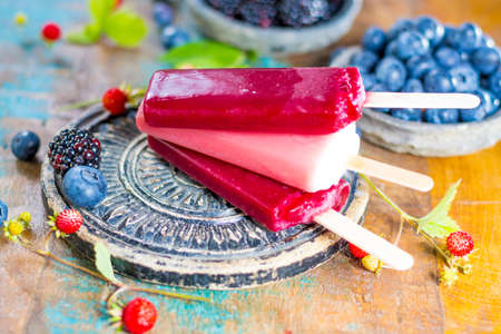 Fresh summer wild blueberries and  bramble berry, strawberry and home made sorbet ice cream popsicles.の写真素材