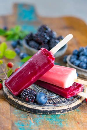 Fresh summer wild blueberries and  bramble berry, strawberry and home made sorbet ice cream popsicles.の写真素材