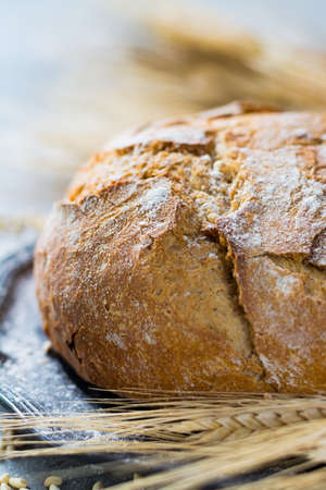 Freshly baked traditional wheat bread and wheat ears on the tableの写真素材