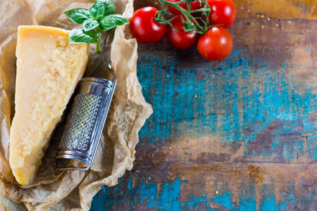 Traditional Italian hard cheese Parmesan with pasta, tomatoes, basil on wrapperの写真素材