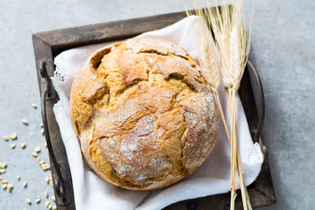 Freshly baked traditional wheat bread and wheat ears on white linen napkinの写真素材