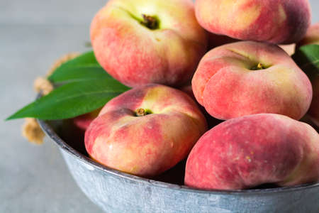 Fresh ripe chinese flat saturn organic peaches with leavesの写真素材