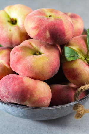 Fresh ripe chinese flat saturn organic peaches with leavesの写真素材
