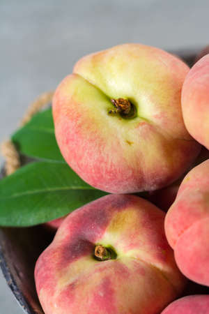 Fresh ripe chinese flat saturn organic peaches with leavesの写真素材