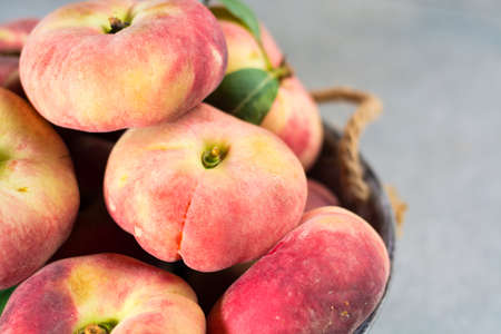 Fresh ripe chinese flat saturn organic peaches with leavesの写真素材