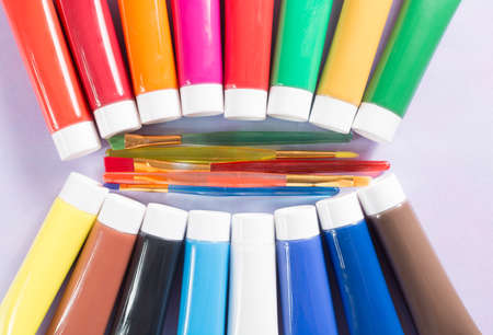 Multicolored rainbow acrylic paints tubes set with five colorful brushes - creative painters conceptの写真素材