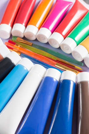 Multicolored rainbow acrylic paints tubes set with five colorful brushes - creative painters conceptの写真素材