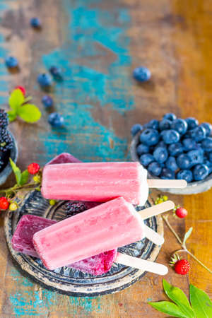 Fresh summer wild blueberries and  brambleberry, strawberry and home made sorbet ice cream popsicles.の写真素材