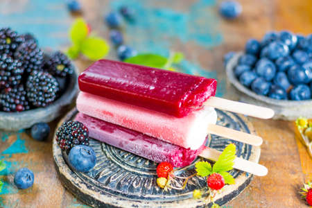 Fresh summer wild blueberries and  brambleberry, strawberry and home made sorbet ice cream popsicles.の写真素材