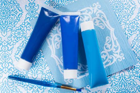 Blue, indigo, cobalt colours - home interieur design concept, on blue-white ornament, tubes with acrylic paint and blue brushの写真素材