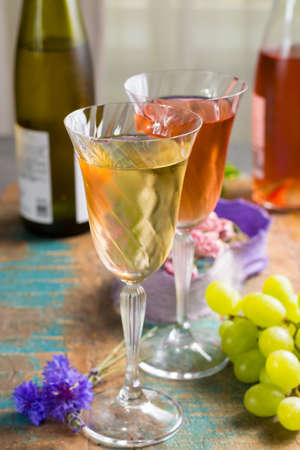 Cold summer wines, white and rose, served in beautiful glasses on terrace in cafe with romantic flowers, close upの写真素材