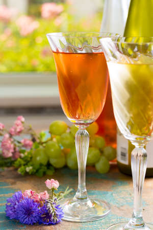 Cold summer wines, white and rose, served in beautiful glasses on the fresh air, outdoor in the green garden with flowers, sunny day, party or romantic conceptの写真素材