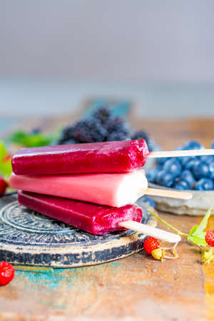 Fresh summer wild blueberries and  brambleberry, strawberry and home made sorbet ice cream popsicles.の写真素材