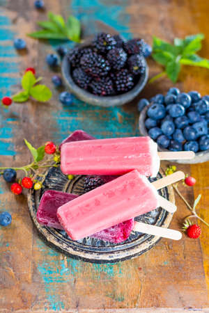 Fresh summer wild blueberries and  brambleberry, strawberry and home made sorbet ice cream popsicles.の写真素材
