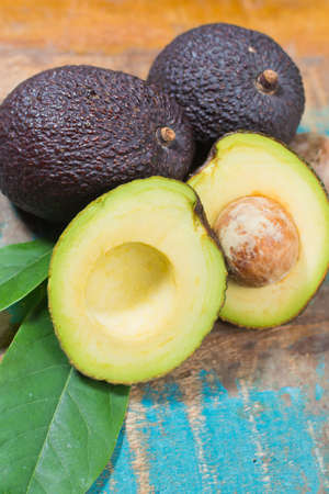 Ripe fresh avocado with leaves on blue wooden table - healthy food concept