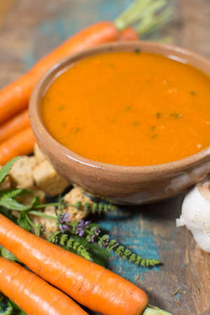Spicy carrot soup with harissa made from hot chili pepper, lemon, garlic, coriander on blue wooden tableの写真素材