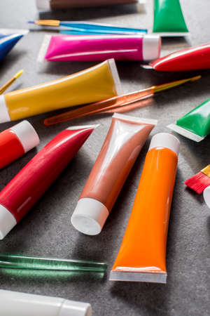 Multicolored rainbow acrylic paints tubes set with five colorful brushes - creative painters concept