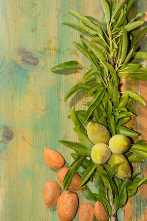 Ripe almonds and fresh green almonds on the branch with leaves on wooden backgroundの写真素材