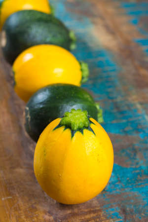 Round green and yellow courgette or zucchini, on wooden background, close up, healthy foodの写真素材