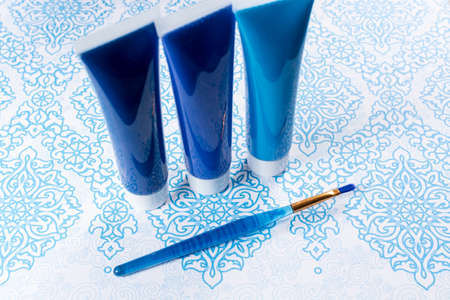 Blue, indigo, cobalt colours - home interieur design concept, on blue-white ornament, tubes with acrylic paint and blue brushの写真素材