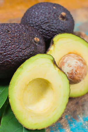 Ripe fresh avocado with leaves on blue wooden table - healthy food conceptの写真素材