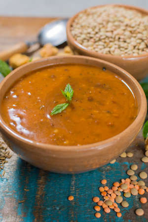 Homemade red lentils soup in old clay bowl with mintの写真素材