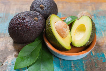 Ripe fresh avocado with leaves on blue wooden table - healthy food conceptの写真素材